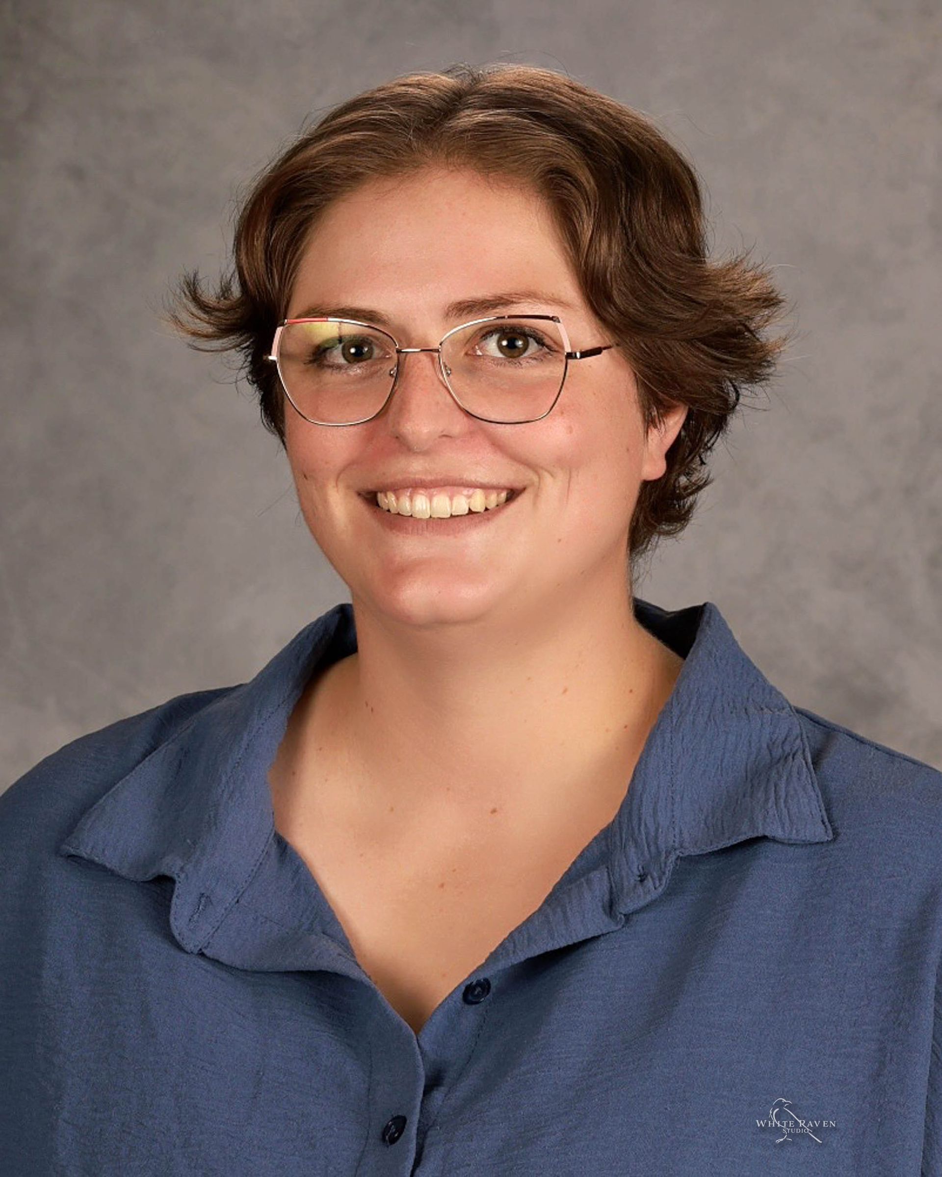 A woman wearing glasses and a black sweater is smiling for the camera.