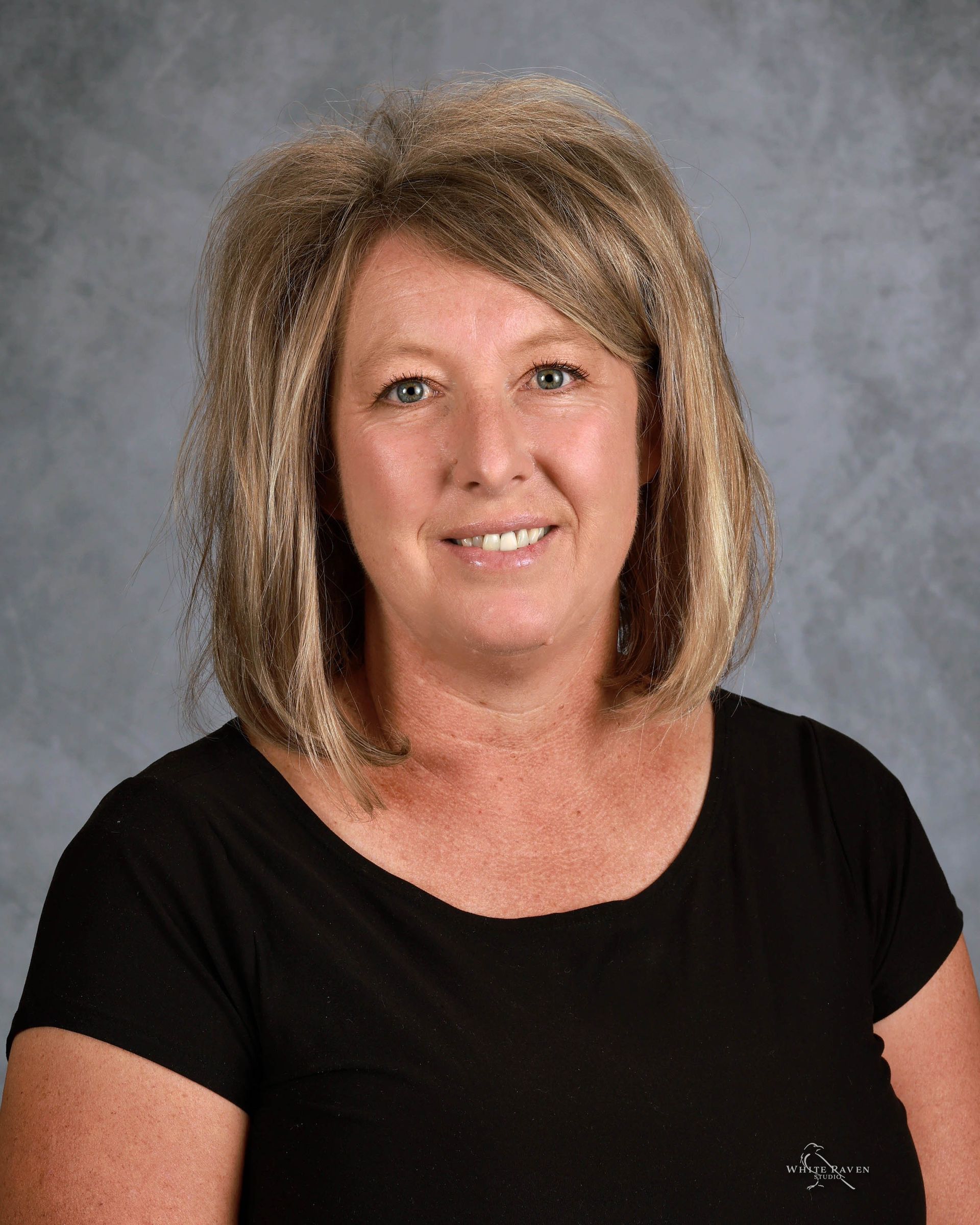 A woman in a green shirt is smiling for the camera.