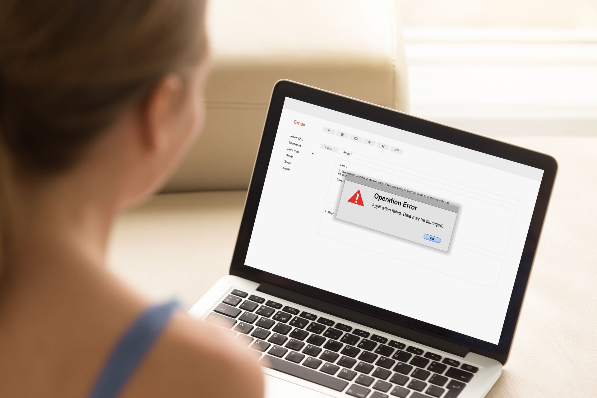 A woman is using a laptop computer with a warning message on the screen.