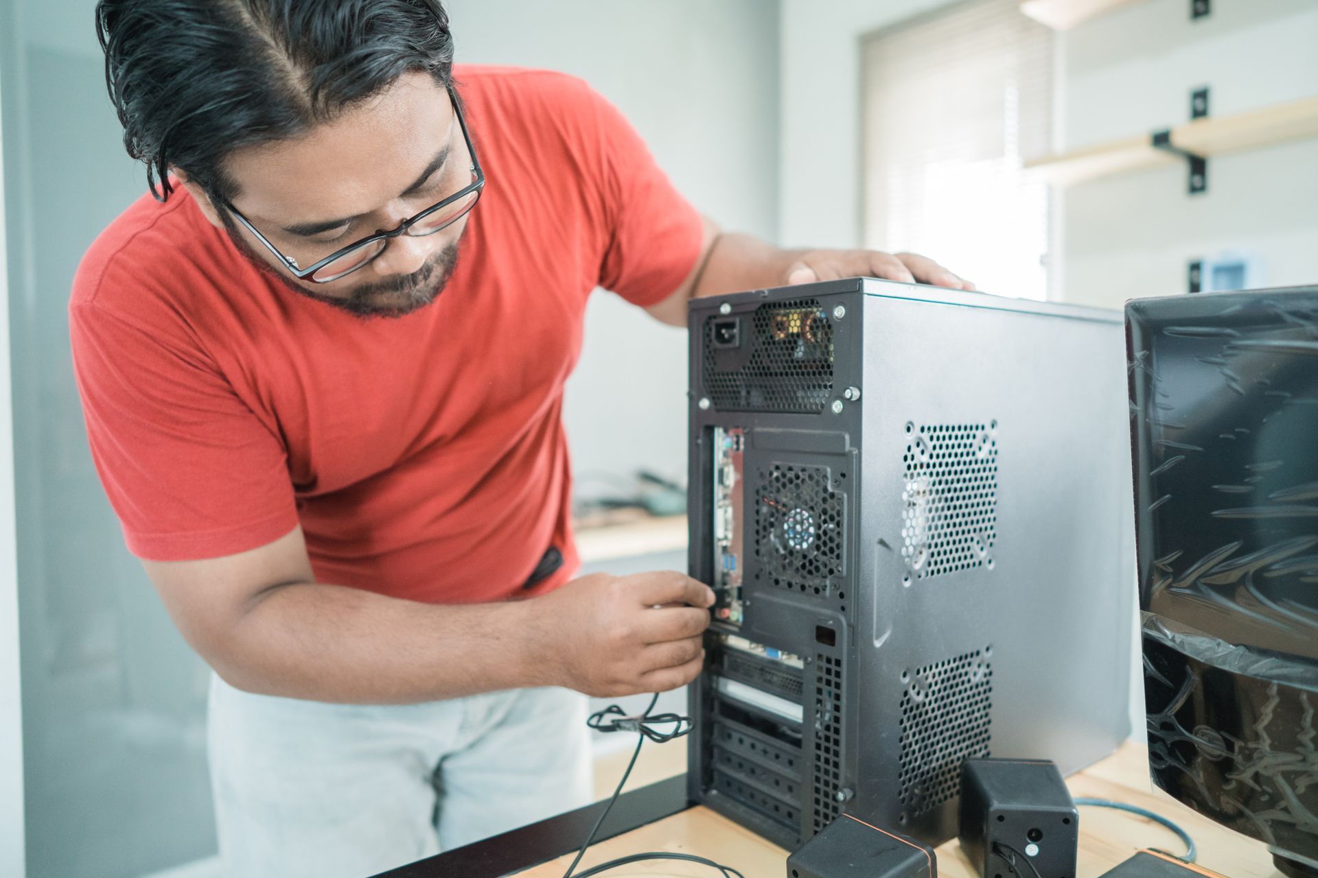 A man in a red shirt is working on a computer.