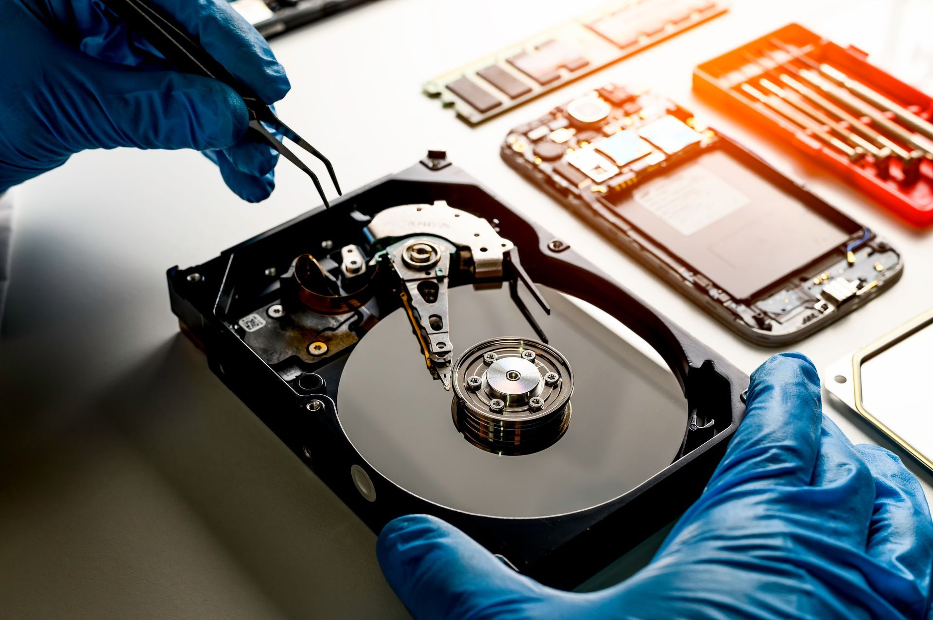 A person wearing blue gloves is working on a hard drive.