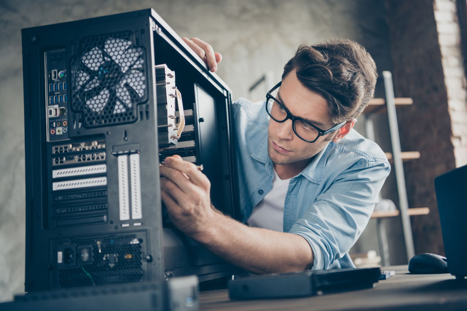 A man wearing glasses is working on a computer.