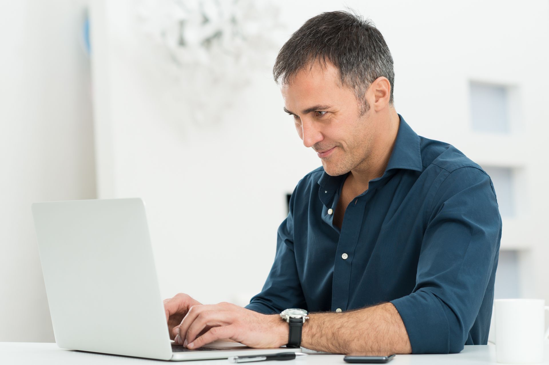 A man is sitting at a desk using a laptop computer.