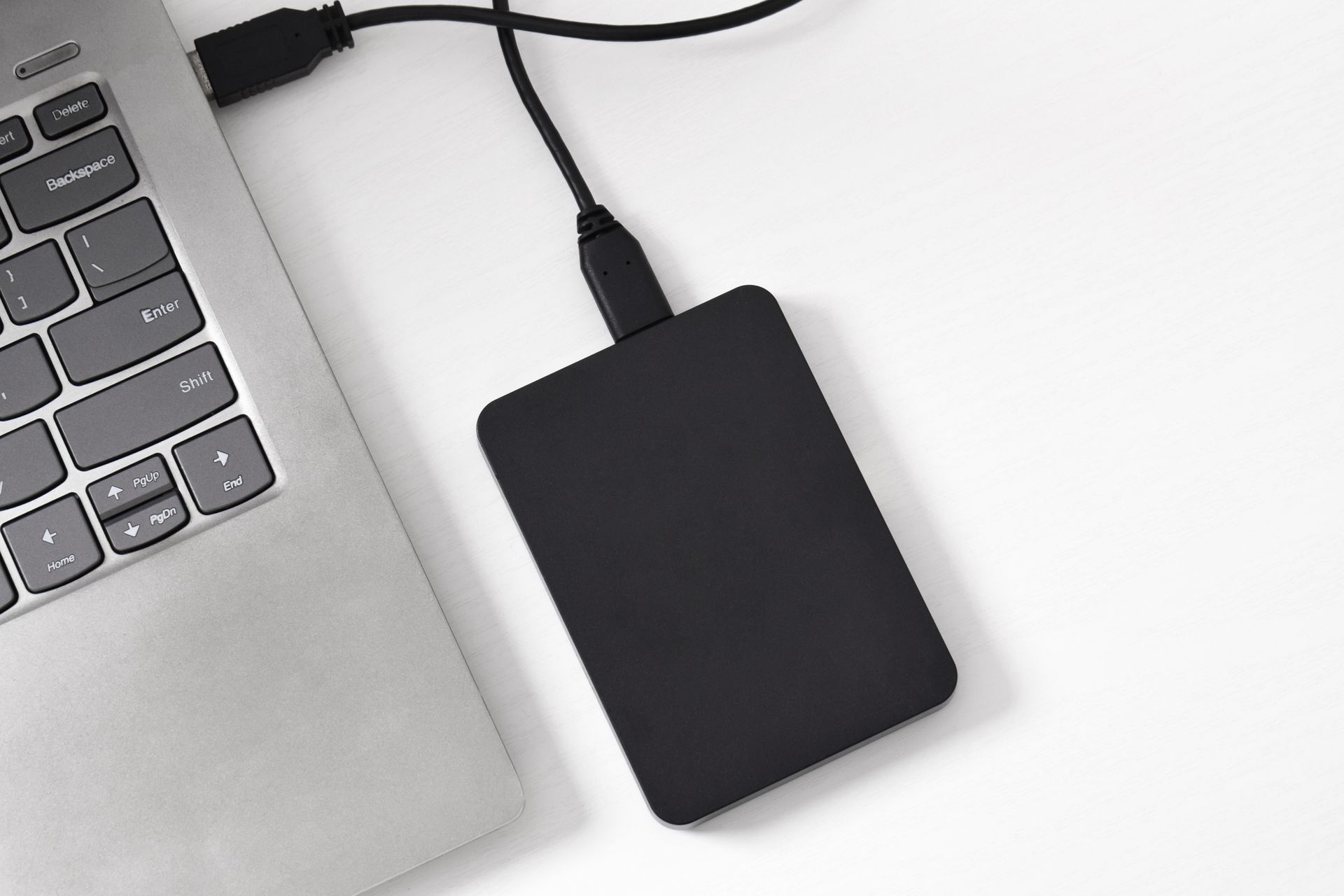 A hard drive is plugged into a laptop computer.