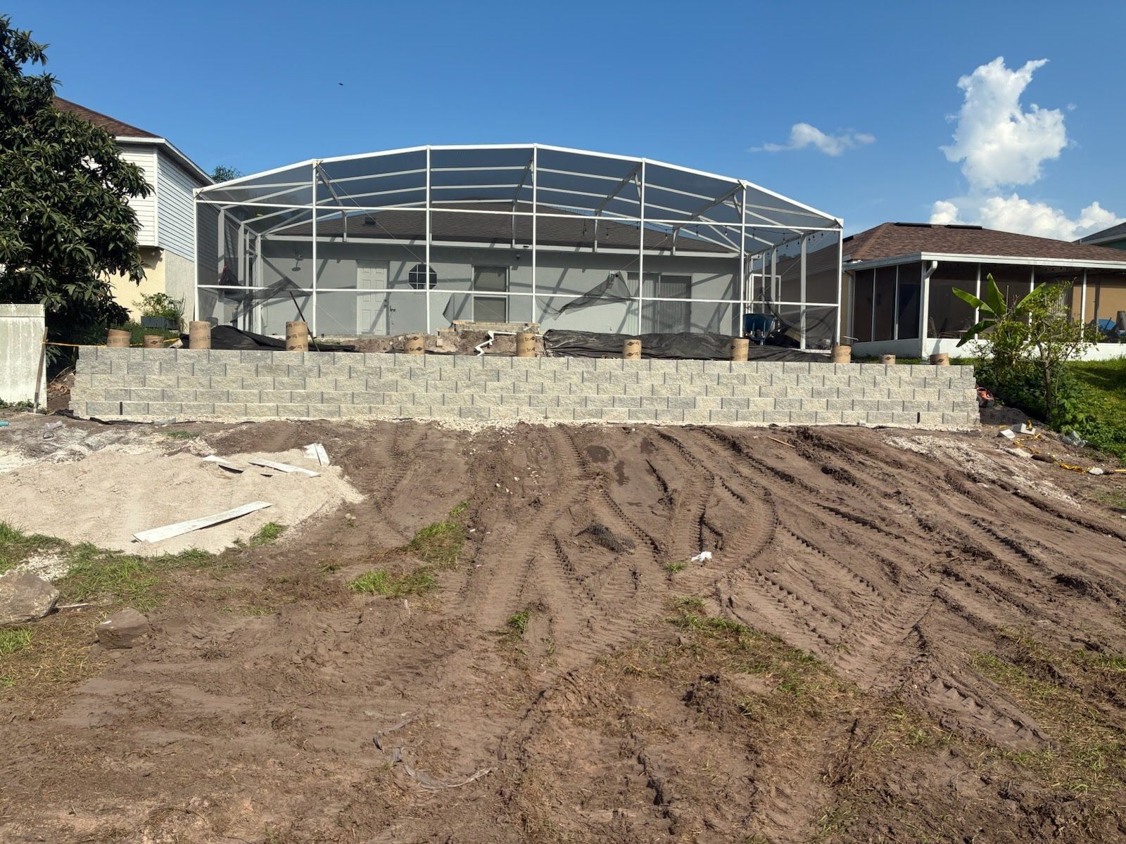 Outdoor construction site with steel-framed building, dirt foreground, and blue sky.