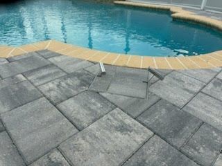 Poolside stone pavers beside a blue swimming pool with a beige coping edge