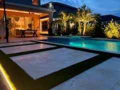 Modern house with illuminated pool and palm trees at dusk