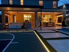 Modern house patio at dusk with warm indoor lights and illuminated poolside walkway