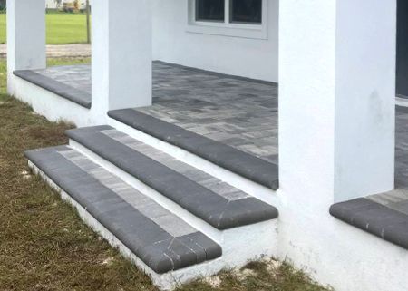 A white house with a porch and steps leading up to it.