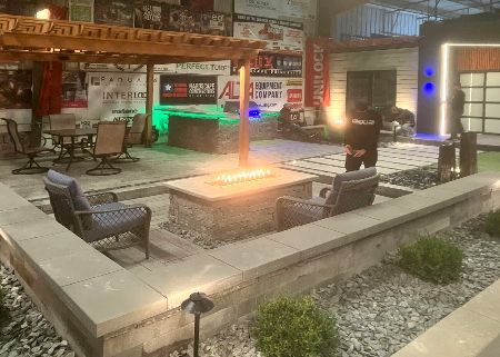 A man is standing in a room with a fire pit and chairs.