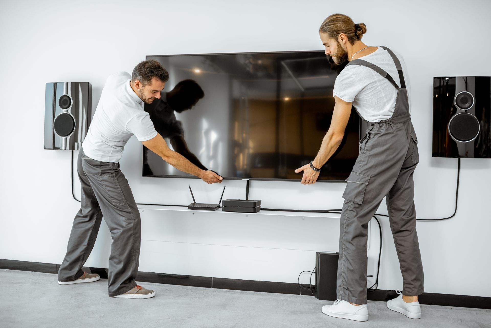 Two men are installing a flat screen tv on a wall.