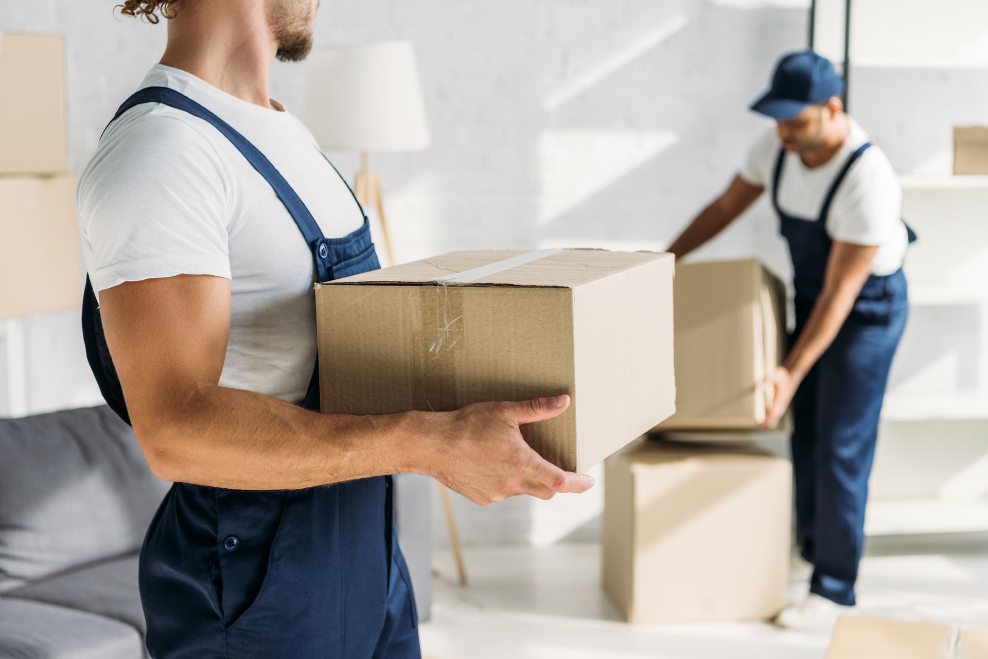 A man is carrying a cardboard box in a living room.