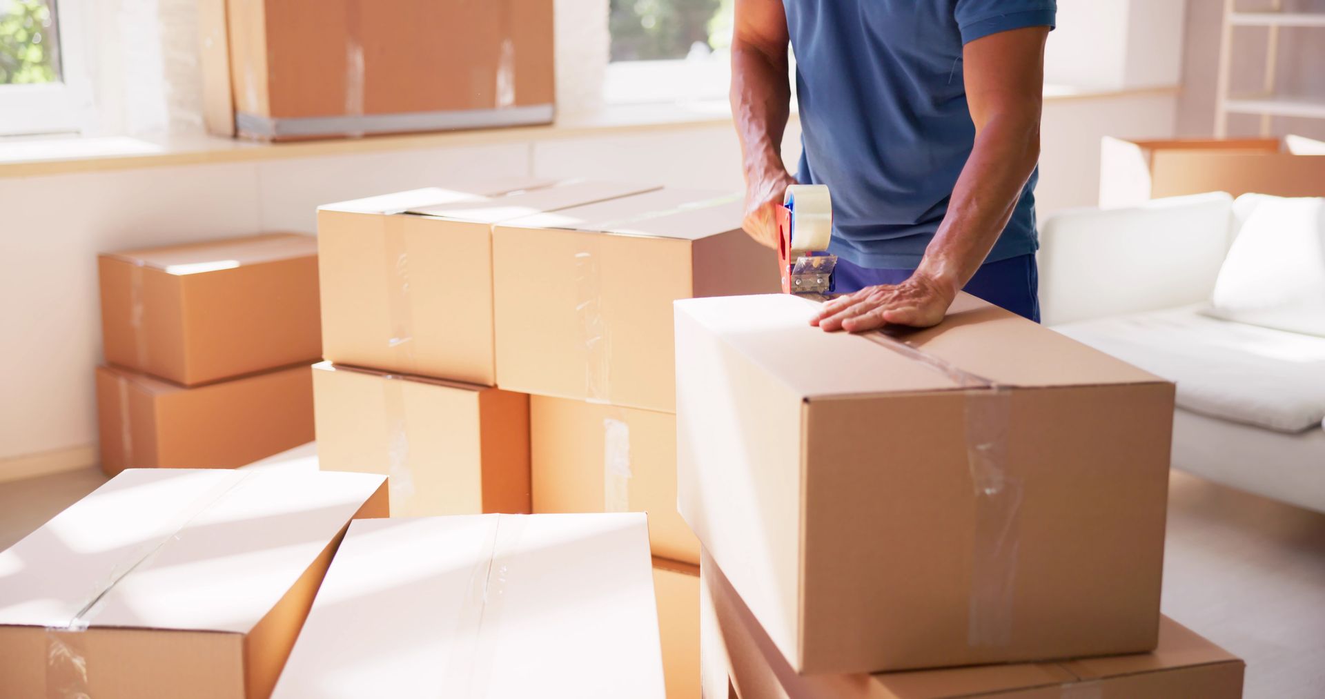 A man is standing next to a pile of cardboard boxes in a living room.