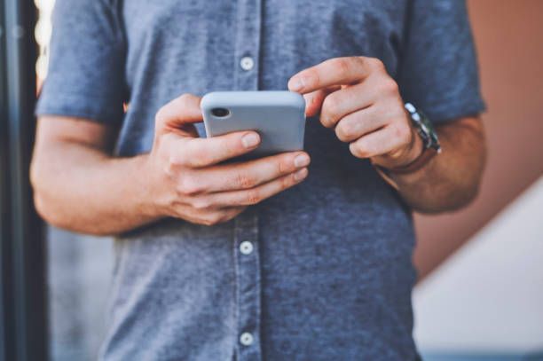 A man is holding a cell phone in his hands.
