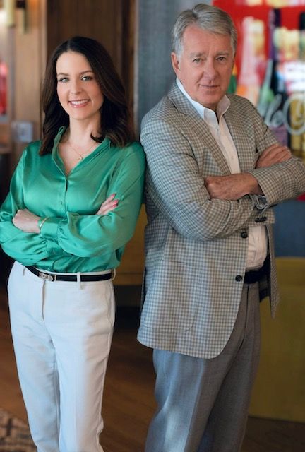 Two people standing indoors, arms crossed, in a casual business setting.
