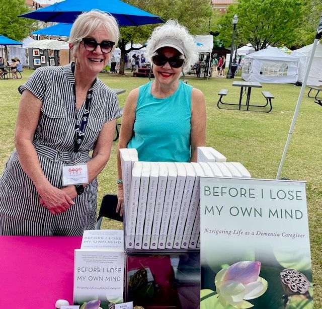 Two women at a book stall with copies of “Before I Lose My Own Mind” on display