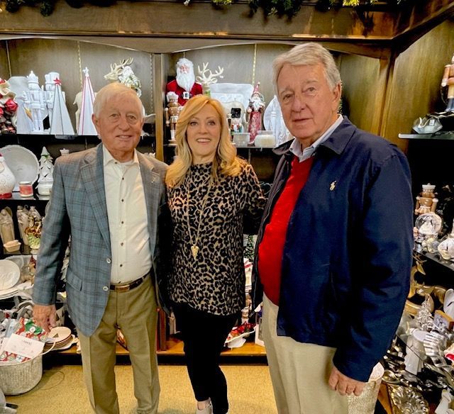 Three people standing in a shop with shelves of decorative ceramics behind them