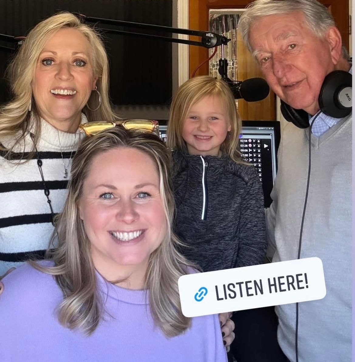 Four people in a radio studio holding a “Listen Here!” sign.
