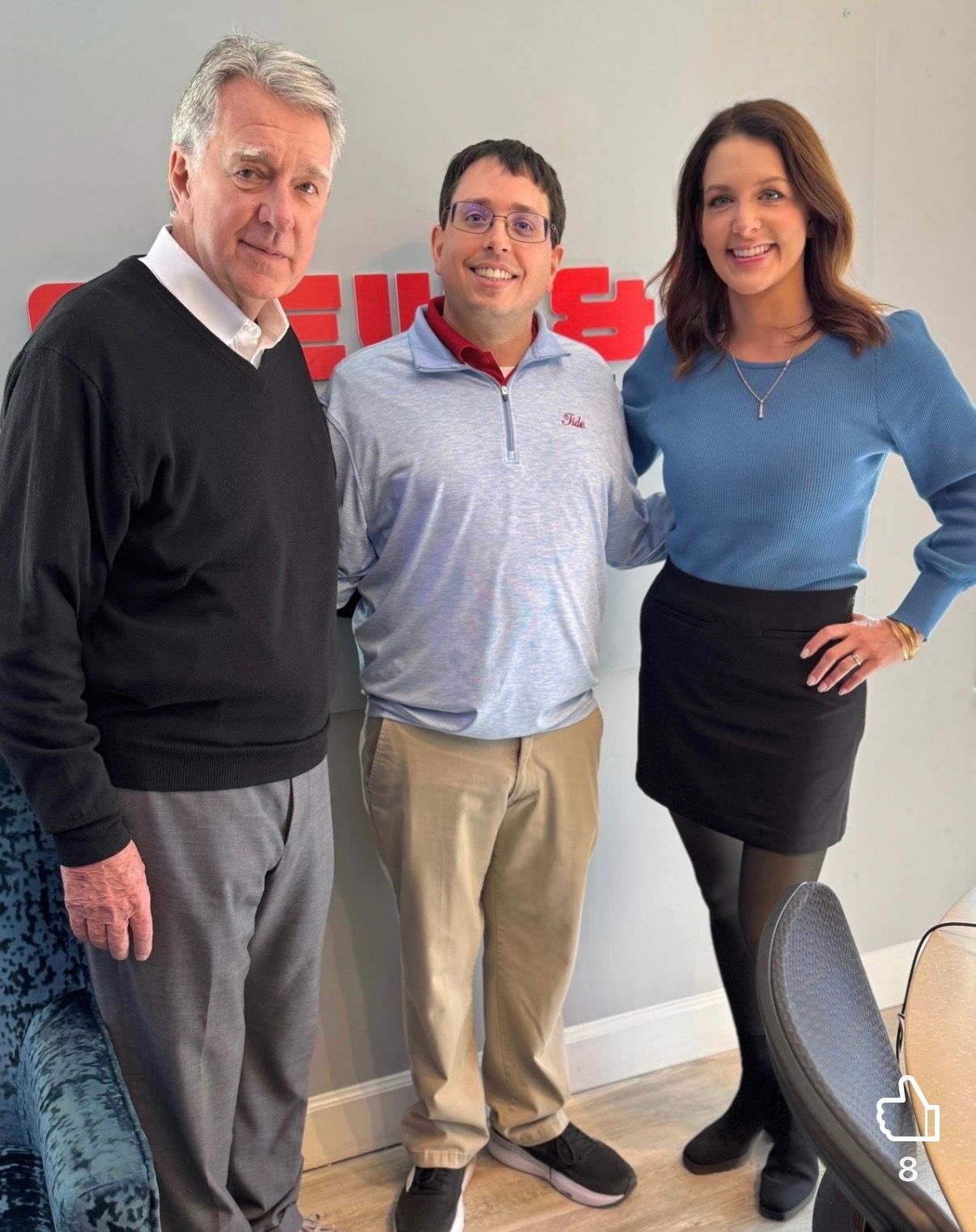 Three people posing indoors, smiling at the camera in casual office attire.