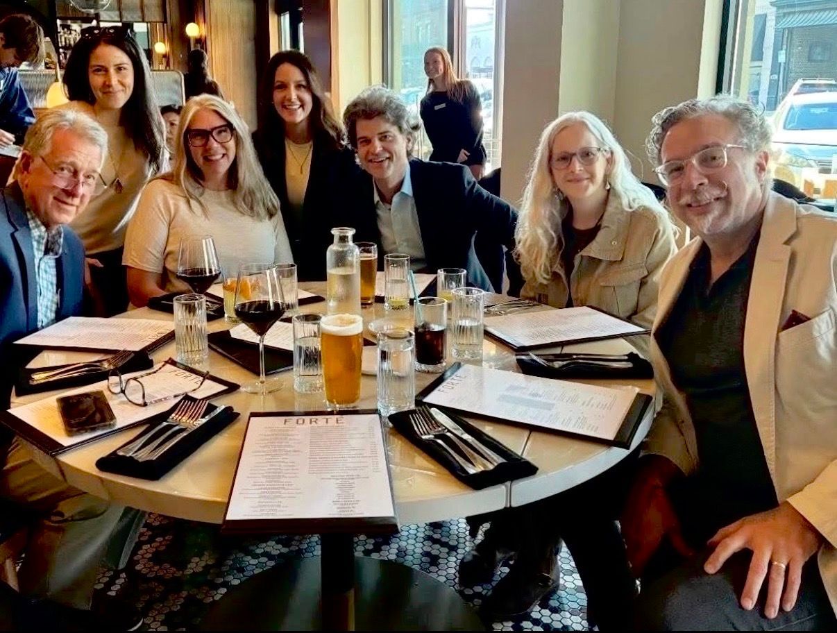 Group of people seated around a restaurant table, smiling and dining together.