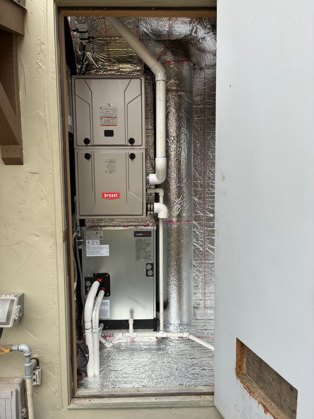 Utility closet with HVAC equipment and insulated ductwork in a narrow opening
