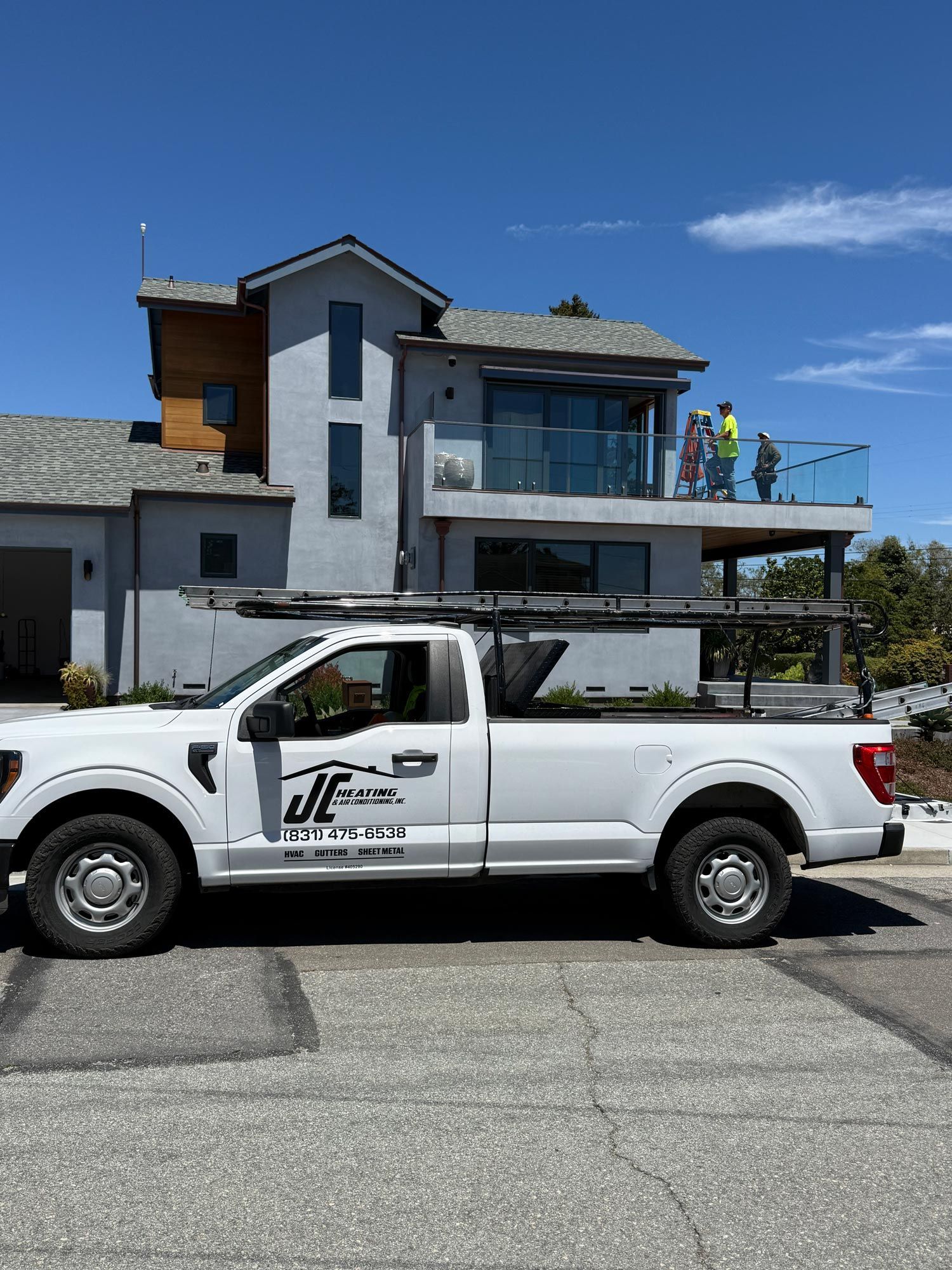 White pickup truck parked in front of a modern house under a clear blue sky