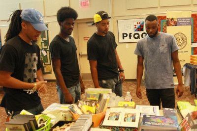 Four people looking at items on a table indoors.