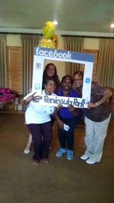 Four people posing with a Facebook photo frame at a Peninsula Park event.