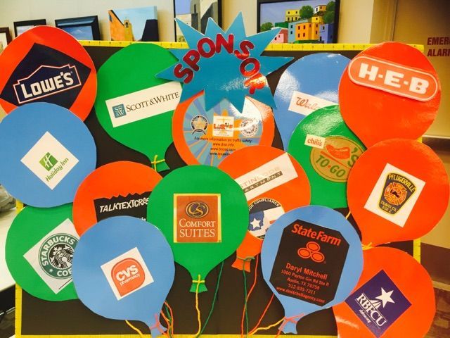Display of colorful paper balloons with various sponsor logos.