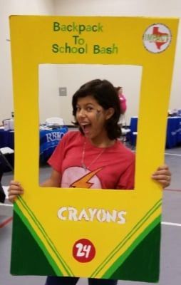 Person posing in a crayon-shaped photo frame at a
