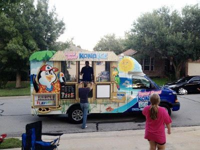 Kona Ice truck with cartoon graphics. People ordering at the service window in a residential setting.