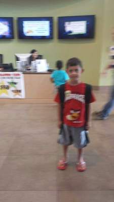 Boy in Angry Birds shirt stands in front of a counter.
