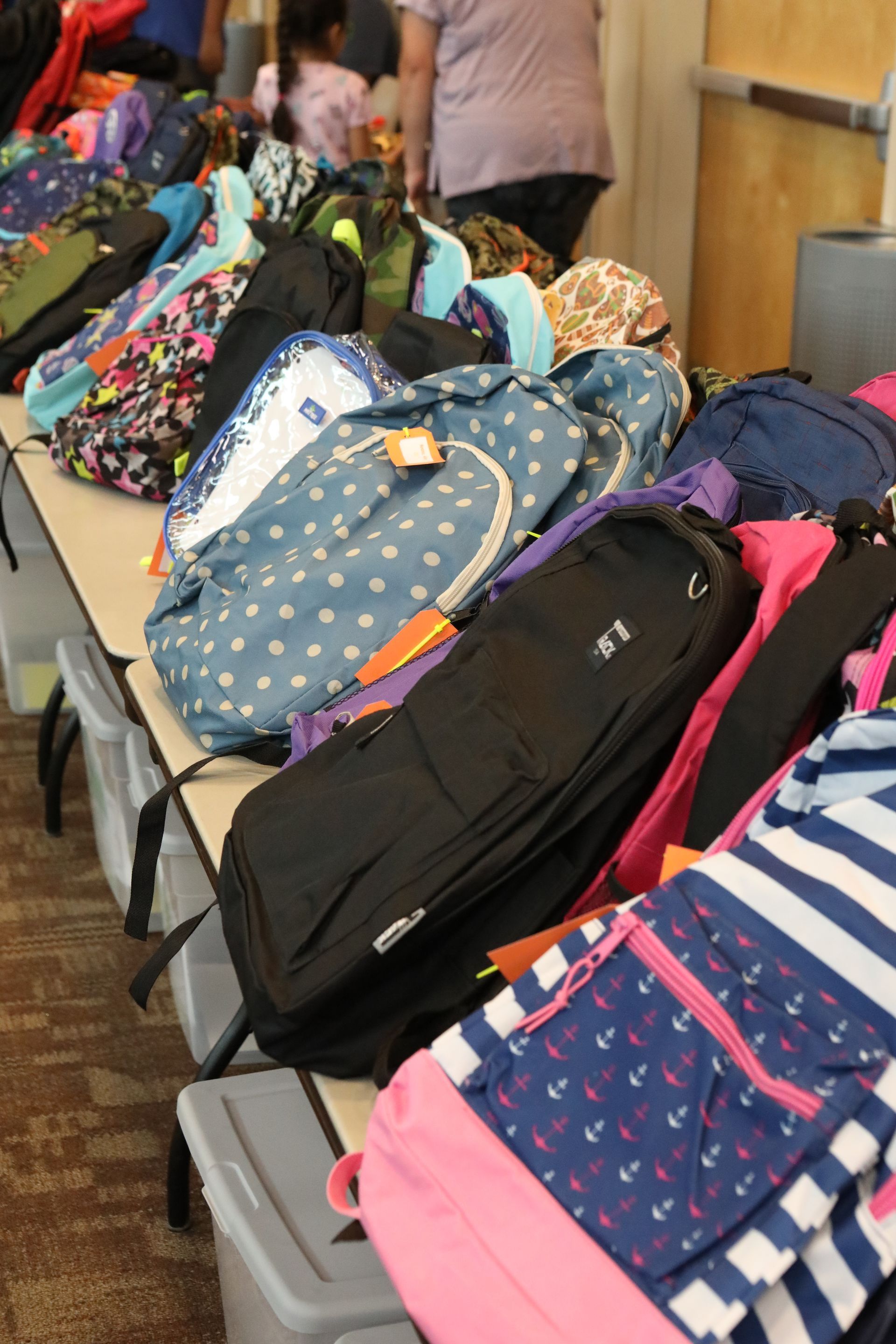 Backpacks on a table, various colors and patterns.