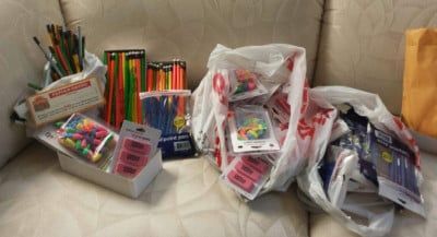 A collection of art supplies, including brushes, pencils, and erasers, spilling from shopping bags.