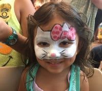 Girl with Hello Kitty face paint smiles.