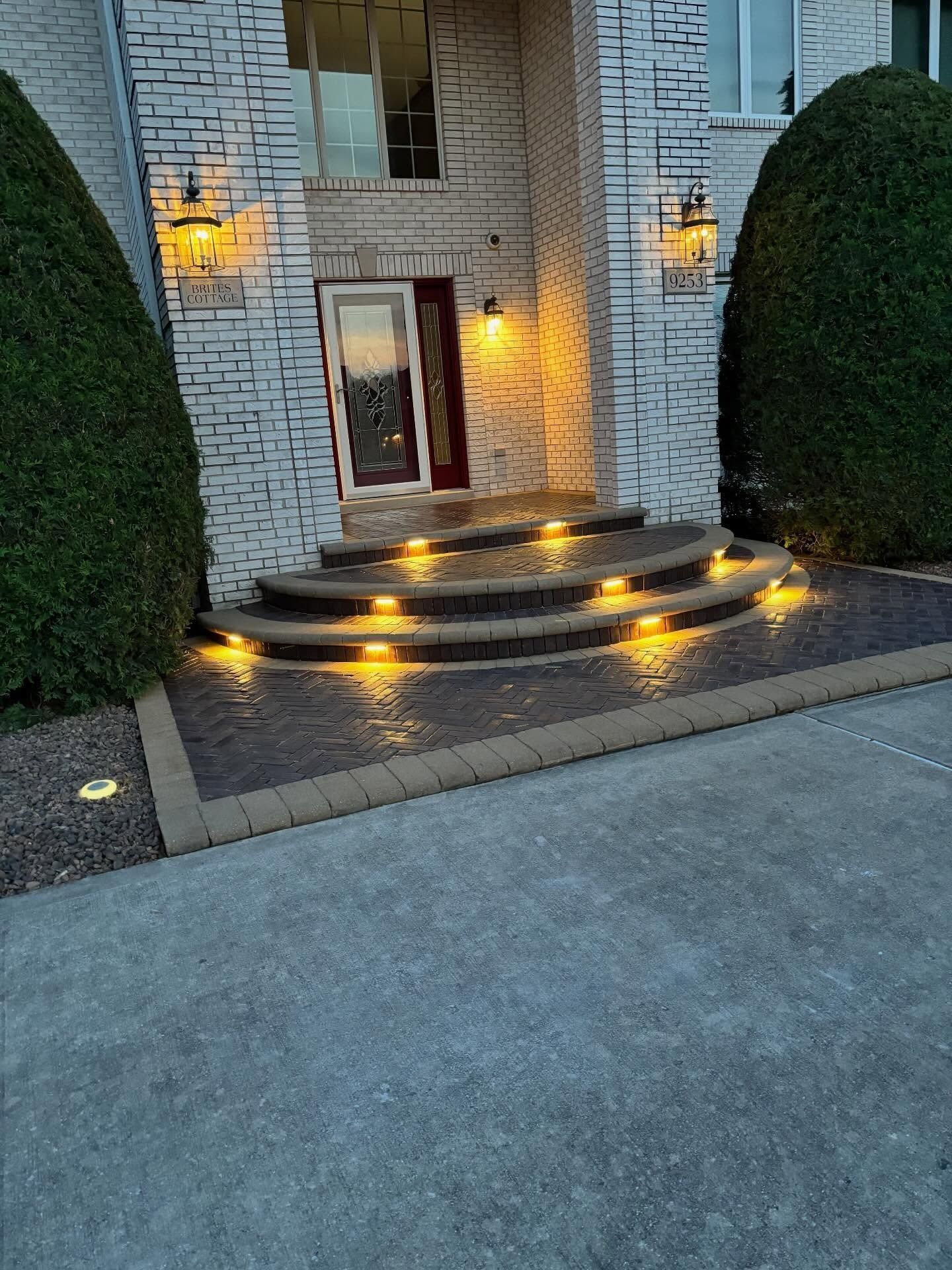 Front steps of a stone house lit by warm yellow pathway lights at dusk