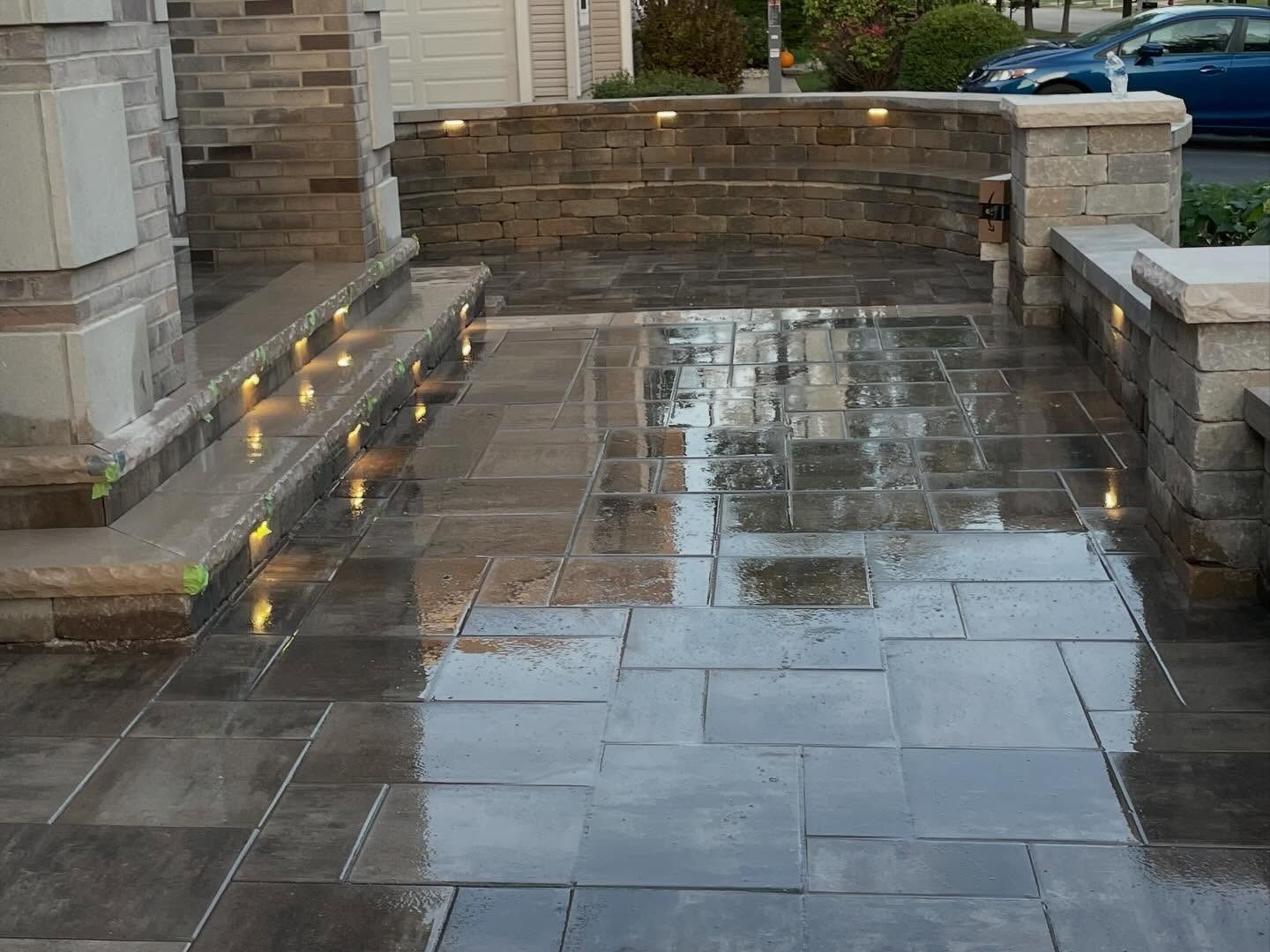 Wet stone patio with lit steps and a low stone wall after rain
