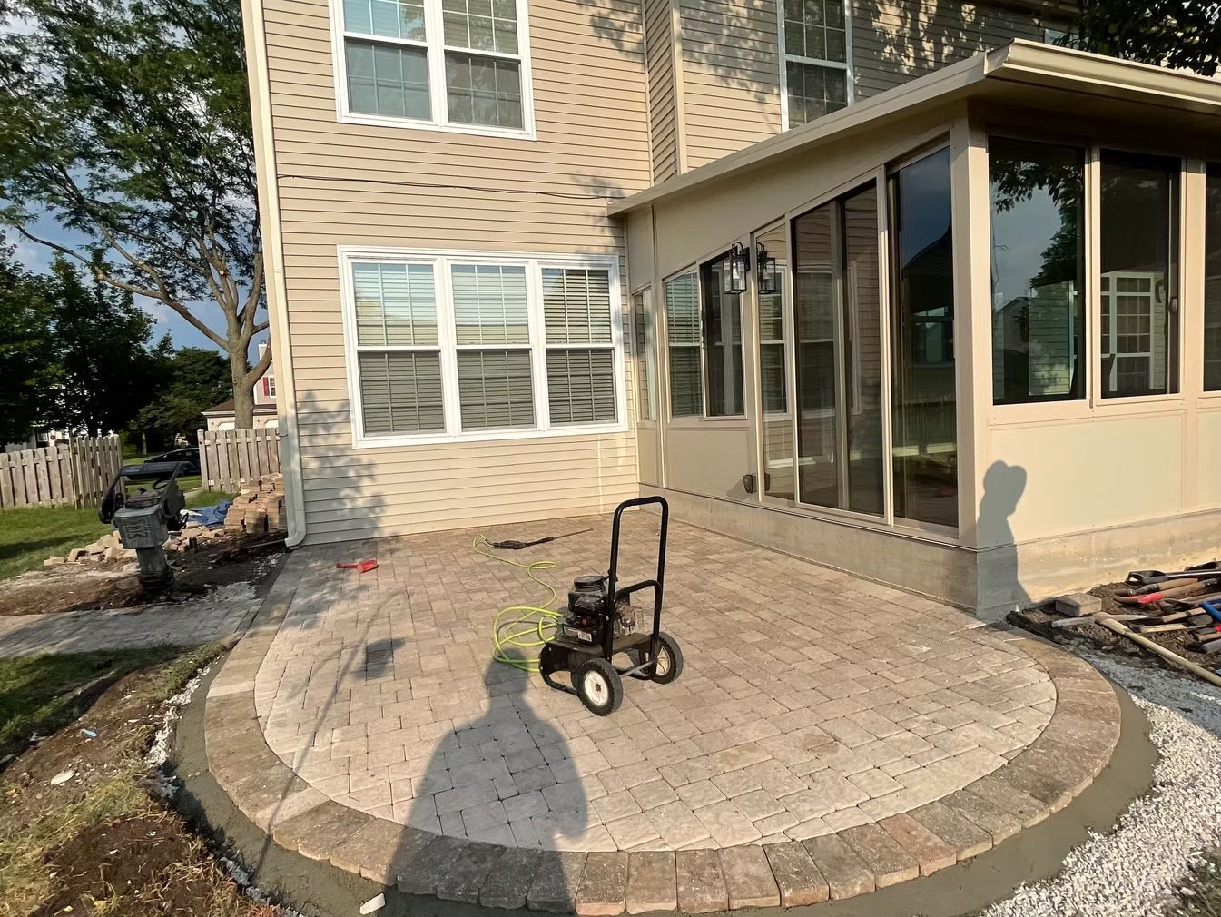 Backyard patio with a black walker on a circular stone pad beside a house and screened porch
