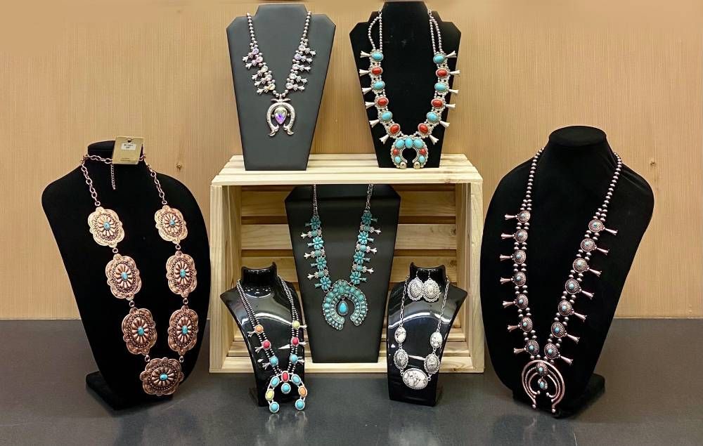 Assorted beaded necklaces and pendant jewelry displayed on black bust stands and trays.