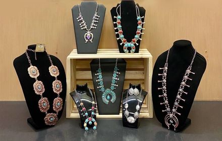 Assorted beaded necklaces and pendant jewelry displayed on black bust stands and trays.
