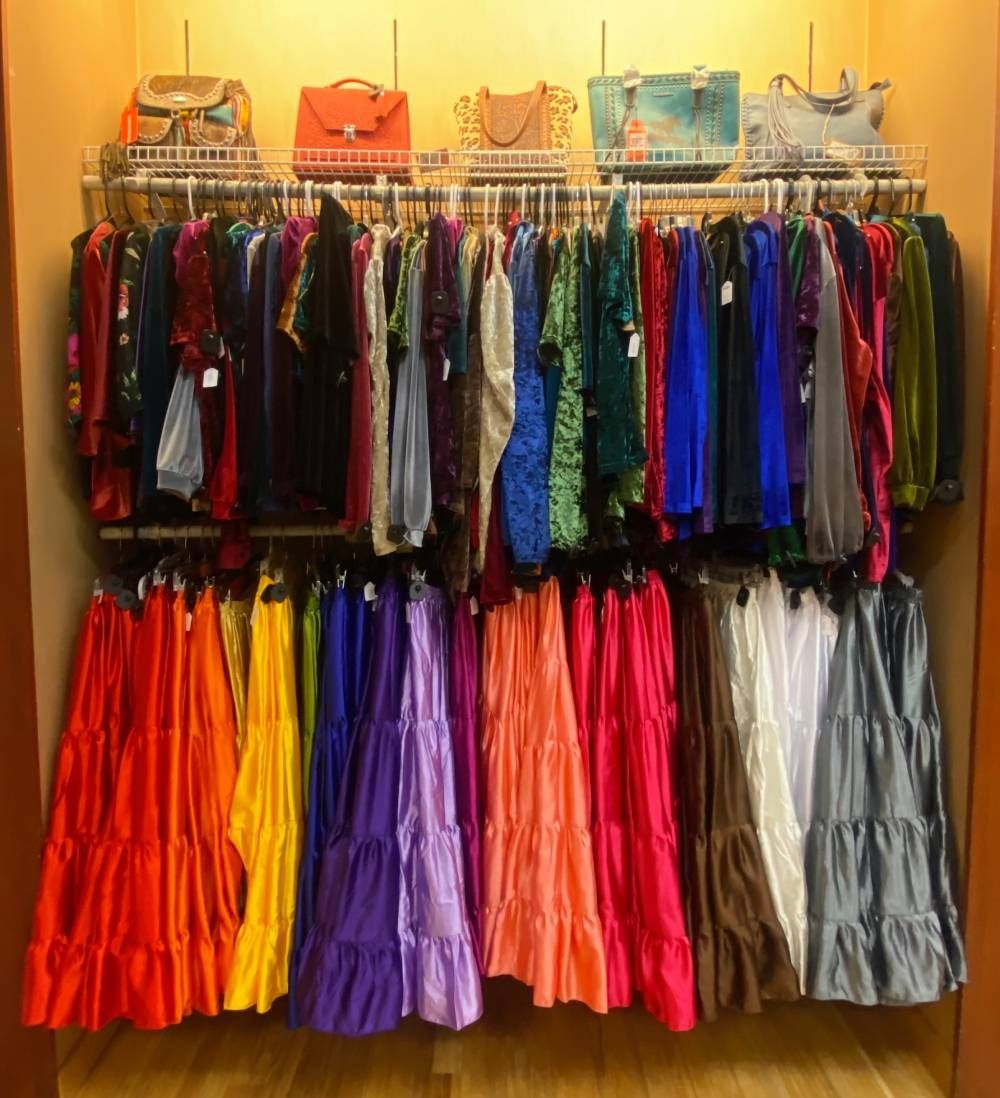 Rack of colorful formal dresses hanging in a store display, including red, blue, purple, pink, and silver gowns