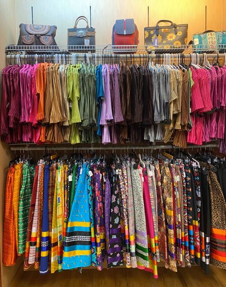 Colorful patterned scarves and handbags displayed on racks in a shop