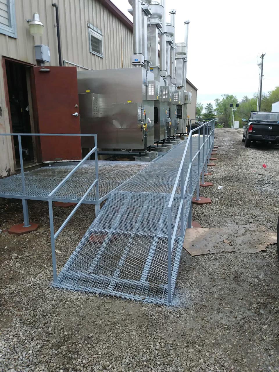 Wheelchair ramp and metal railing outside a building on a gravel lot