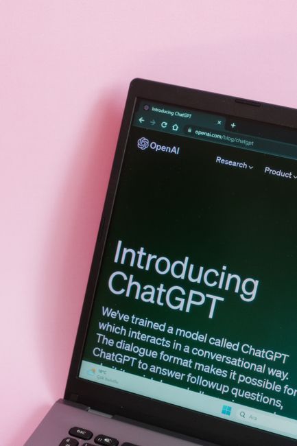 Laptop screen showing the ChatGPT homepage on a dark interface against a pink background
