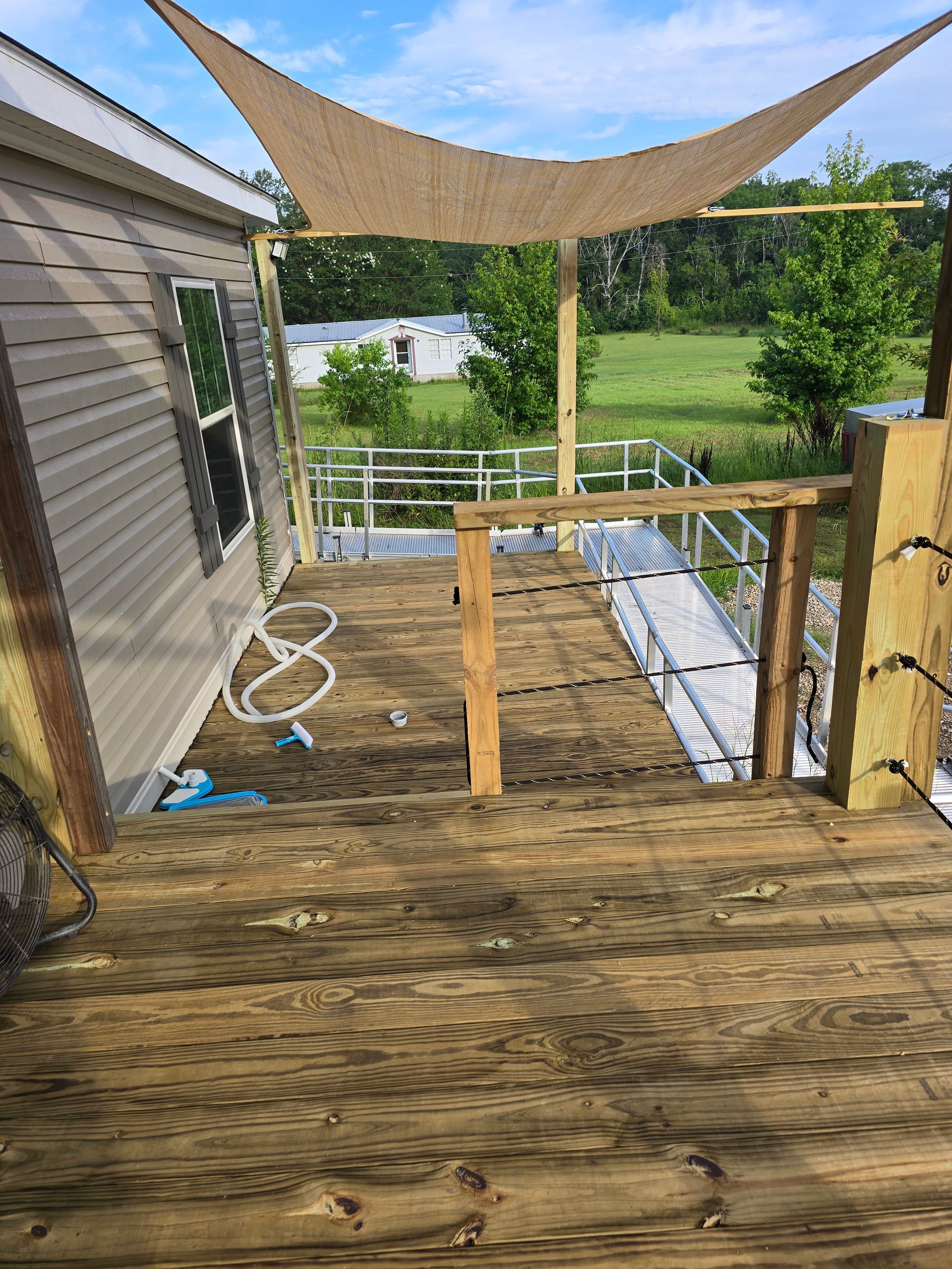 Wooden deck with partial shade cover, next to a home.