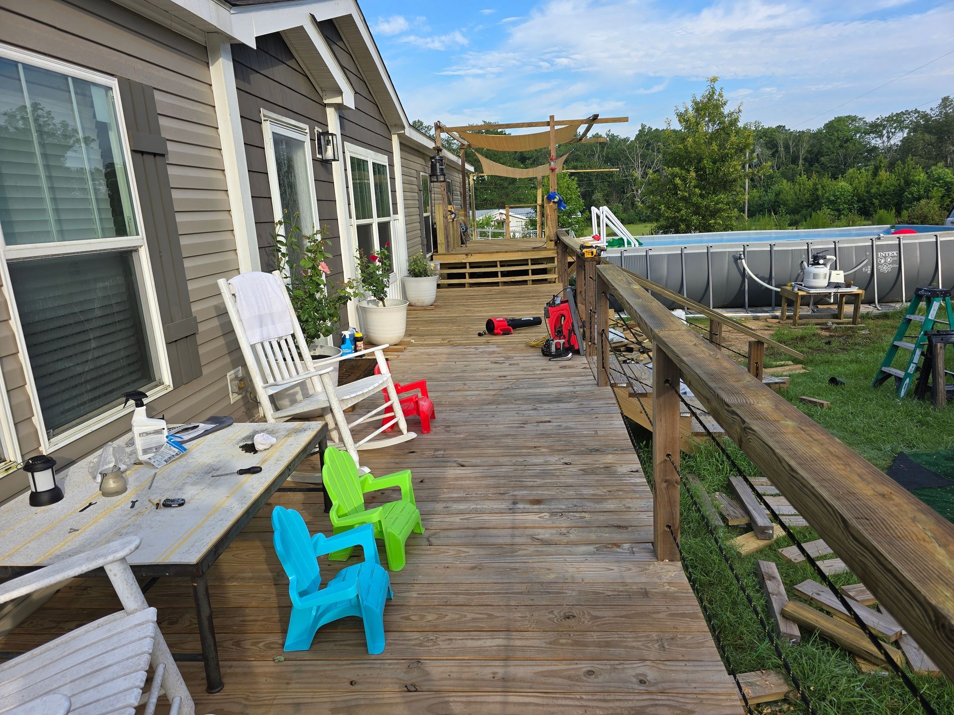 Wooden deck with house, chairs, and above-ground pool in the backyard.