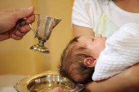 Adult holding a chalice over a baby's head during a baptism ceremony