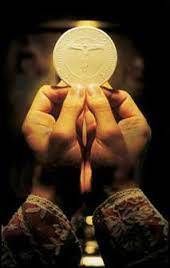 Hands holding a lit white candle against a dark background