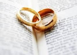 Two gold wedding rings resting on an open book page about love