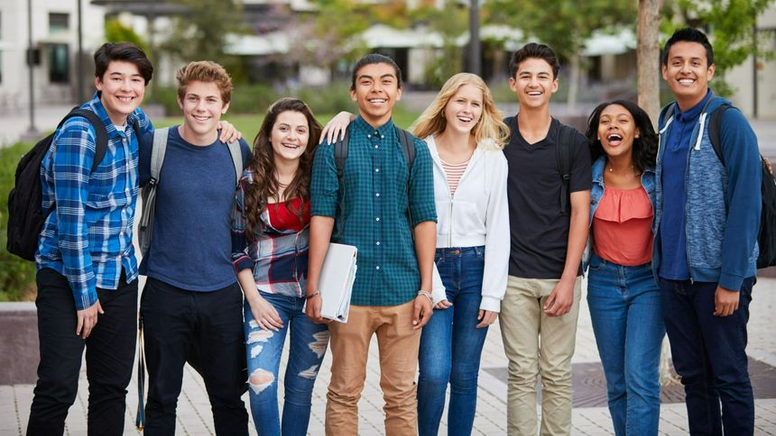 A smiling group of seven people standing outdoors on a city street, facing the camera.